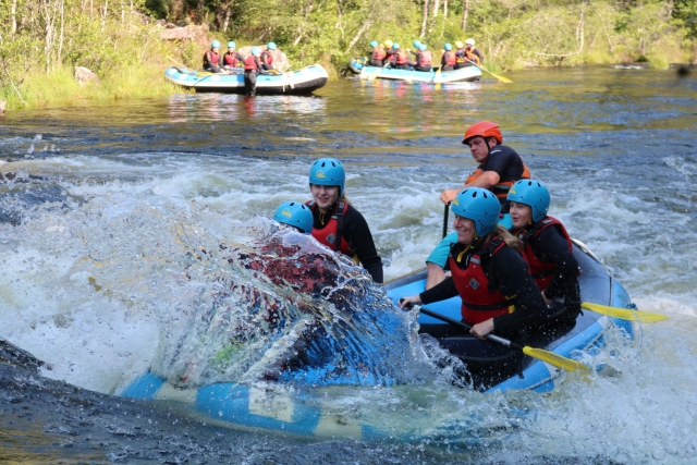  Mujes con cascos azules y La flotabilidad roja ayuda al rafting mientras el agua salpica