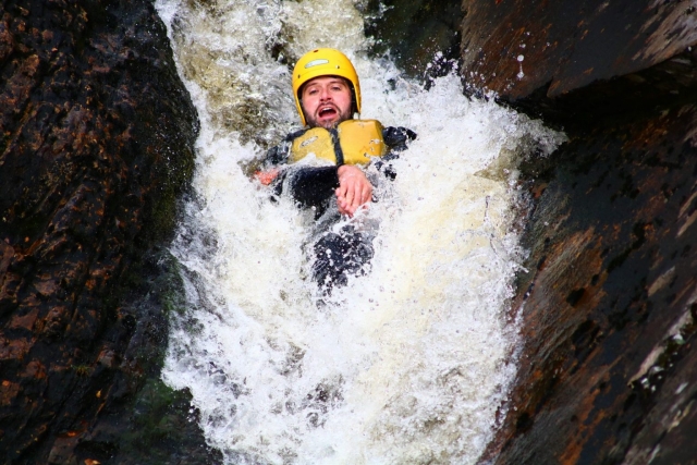 Hombre con casco amarillo haciendo barranquismo 