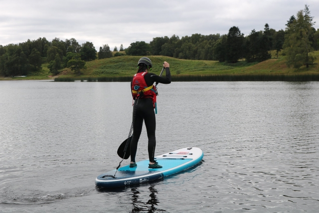 Niña vistiendo ayudas de flotabilidad rojas y casco negro haciendo paddleboard