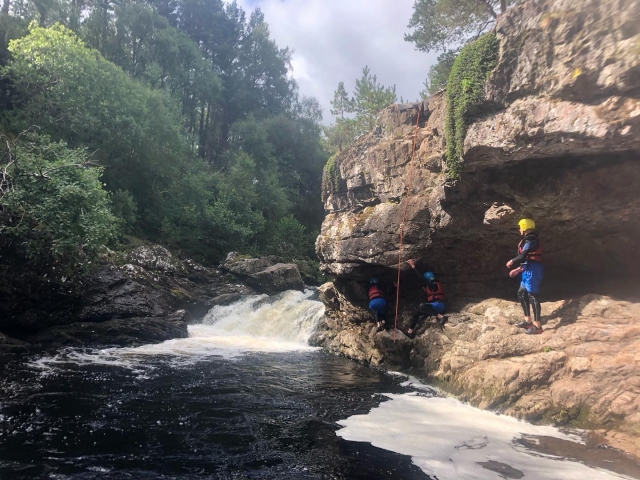  Tres personas con cascos amarillos y ayudas de flotabilidad rojas espeleología y escalada duranle su sesión de barranquismo 