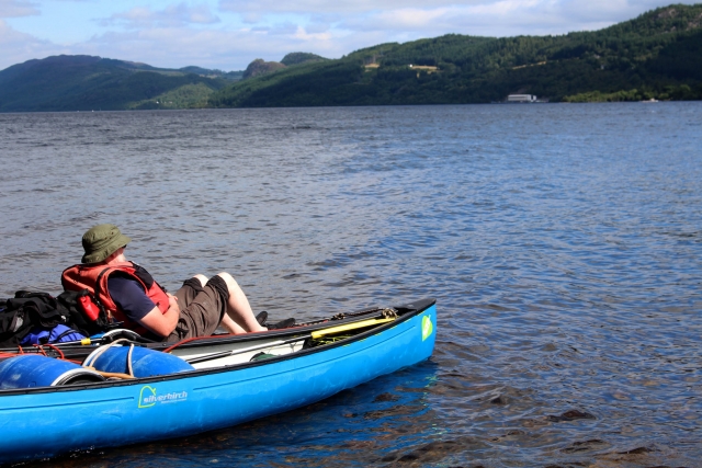  Hombre con sombrero verde y ayudas de flotabilidad rojas disfrutando de la vista duranle su experiencia en kayak 