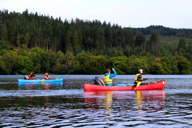 Dos hombres, con ayudas de flotabilidad amarillas, y una mujer y un hombre, con ayudas de flotabilidad rojas, navegando en kayak alrededor de Great Glen 