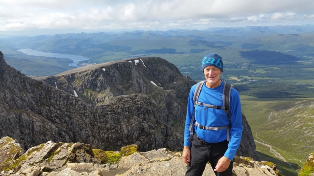  Hombre sonriendo con camisa azul duranle su sesión de escalada en el Ben Nevis