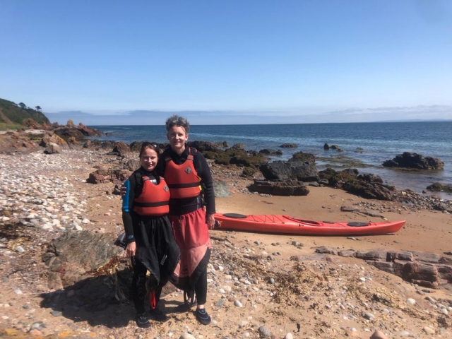  Pareja chavo con ayudas de flotabilidad rojas, posando y sonriendo antes de navegar en kayak 