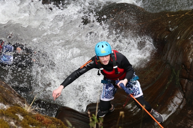 Niño escalando las cataramarras y usando casco azul y flotadores rojos