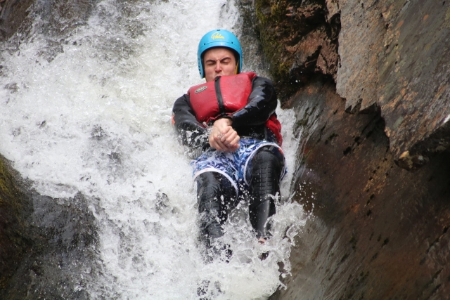 Niño cerrando los ojos, usando casco azul y flotadores rojos saltando desde las cataramarras