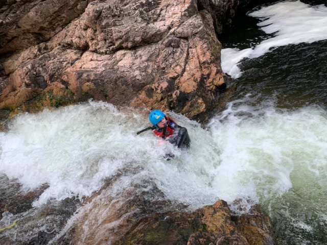 Niña con casco azul y flotadores rojos nadando y saltando desde las cataramarras