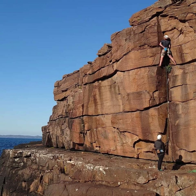  Dos niños con cascos blancos y camisetas negras duranle su curso de escalada 