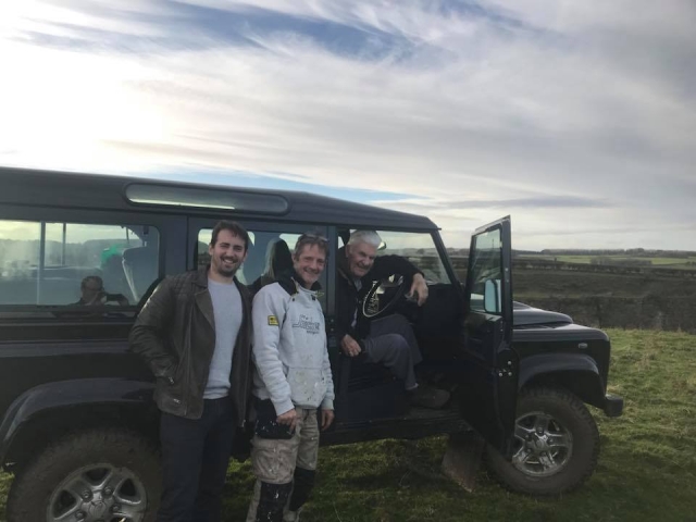Tres hombres con jerseys blancos y negros sonriendo y a punto de manejan un 4x4 como parle de su sesión multiaventura