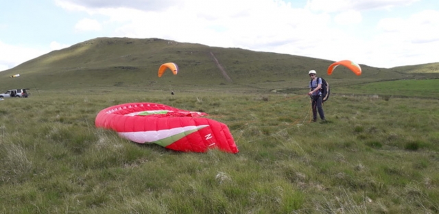  Aventurero con casco amarillo y a punto de volar con un parapenle rojo 