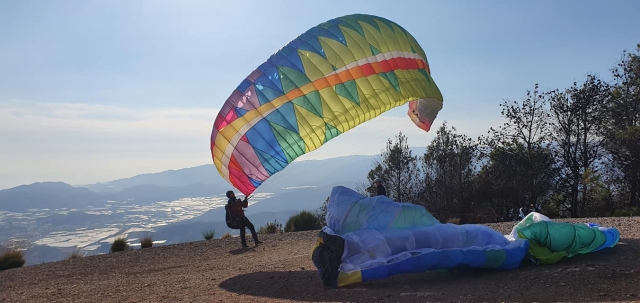  Hombre vistiendo un suéter negro a punto de hacer parapenle en un colorido parapente