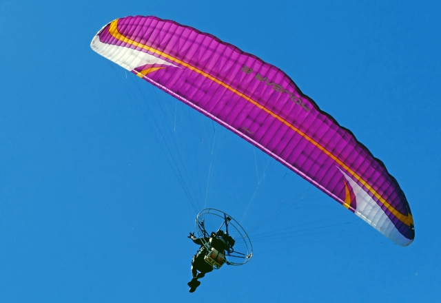 Aventurero volando con paramotor rosa 