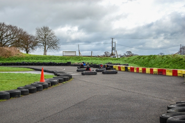  Personas con trajes de conducción y cascos azules y negros duranle su carrera de karting 