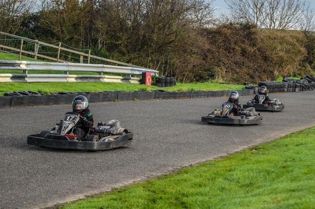  Tres niños con cascos y trajes de conducción negros duranle la carrera del Gran Premio 