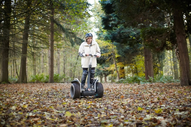  Mujer con chamarra rosa, casco negro, sonriendo y haciendo segway en el parque