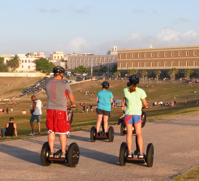  Familia de tres personas con cascos negros y haciendo segway por el parque