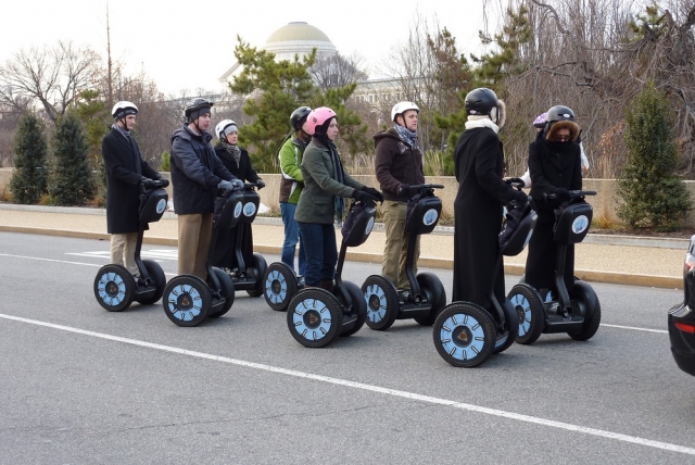  Personas con abrigos negros y cascos blancos divirtiéndose con su aventura en segway 