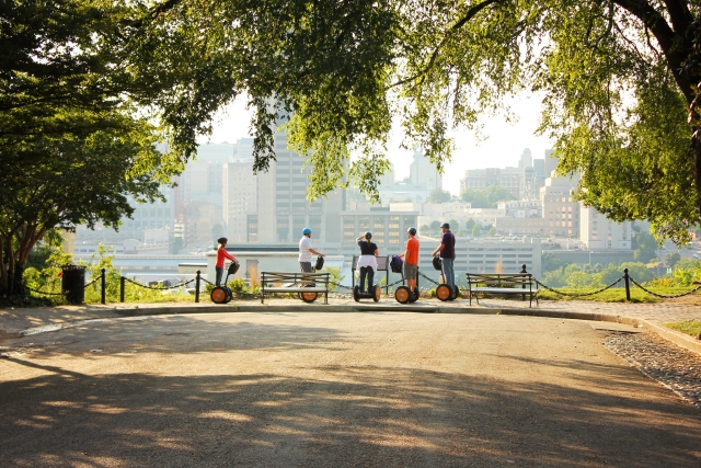  Personas en segways al fondo contemplando la ciudad en el parque 
