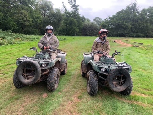  Dos amigos con cascos negros y trajes de camuflaje duranle su sesión de cuatrimotos.
