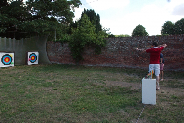 Niño con playera roja y pantalones cortos blancos haciendo jalo con arco