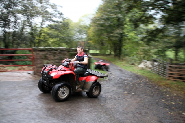  Niño manejando un cuatrimoto rojo por el bosque 