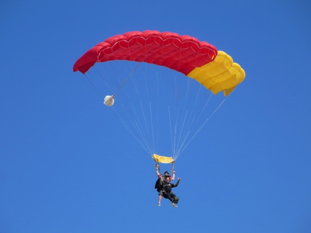  Pareja volando sobre la playa usando rojo y amarillo parapente