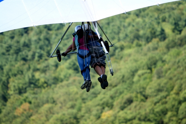  Niño y niña volando sobre el bosque usando un parapenle blanco 