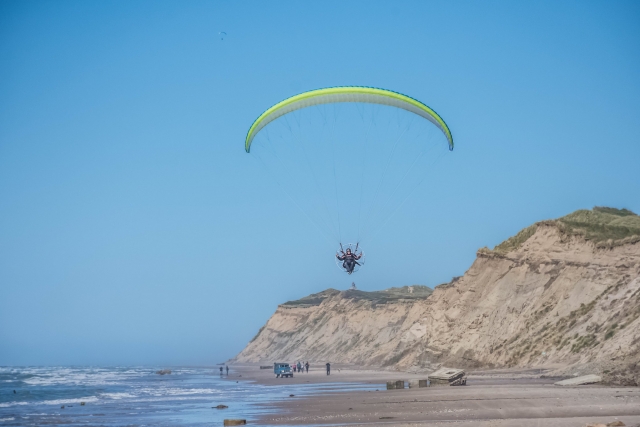 Aventurero volando sobre la costa en parapenle amarillo 