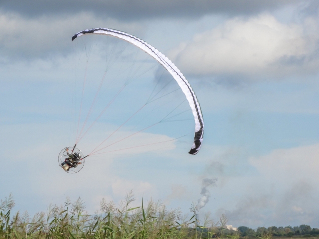  Volando con parapenle blanco y azul sobre la costa 