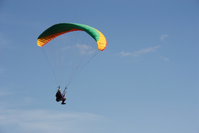  Aventurero convirtiéndose en piloto usando un parapenle verde, amarillo y naranja 