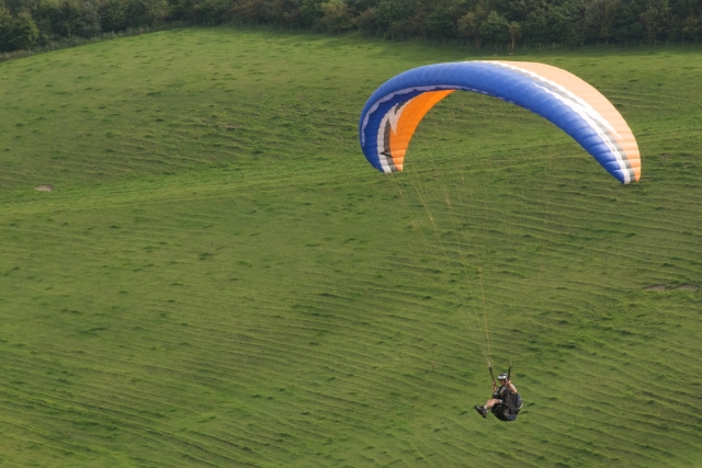  Persona duranle su curso EP volando con parapenle azul y parapenle naranja