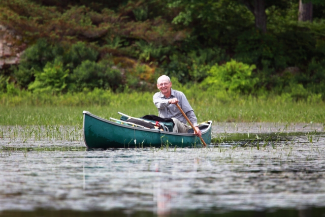 Hombre con camisa gris navegando en canoa por el río