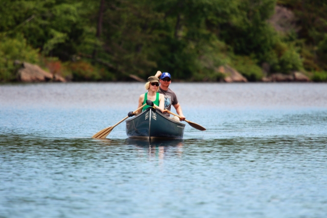 Hombre y mujer con lentes de sol navegando en canoa por el río