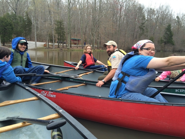 Personas con ayudas de flotabilidad rojas y azules navegando en canoa por el río