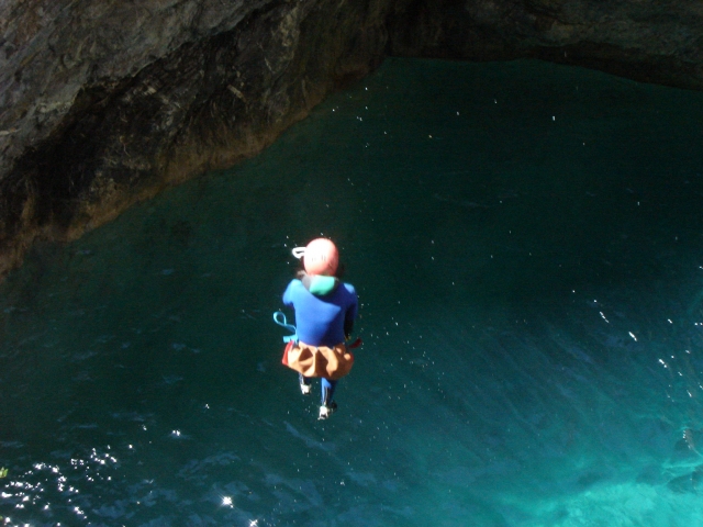  Niña saltando y a punto de nadar. Lleva un traje de neopreno naranja y azul.
