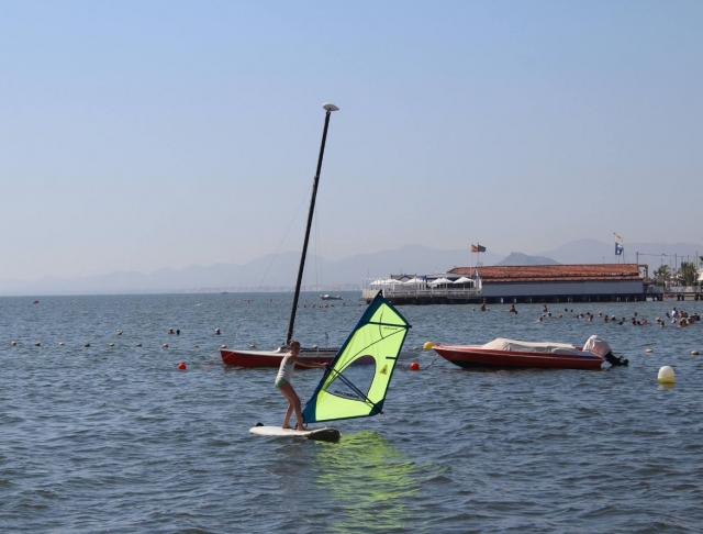Alumna de windsurf levantando la tabla
