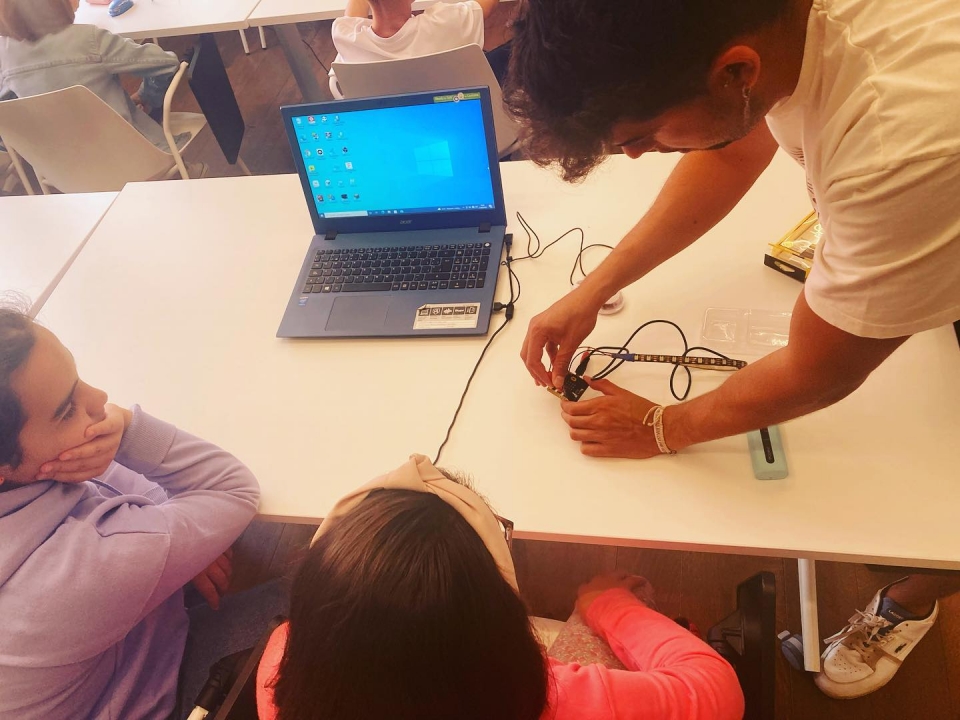 Un instructor acreditado explica a un par de niñas el funcionamiento de un sistema de circuitos