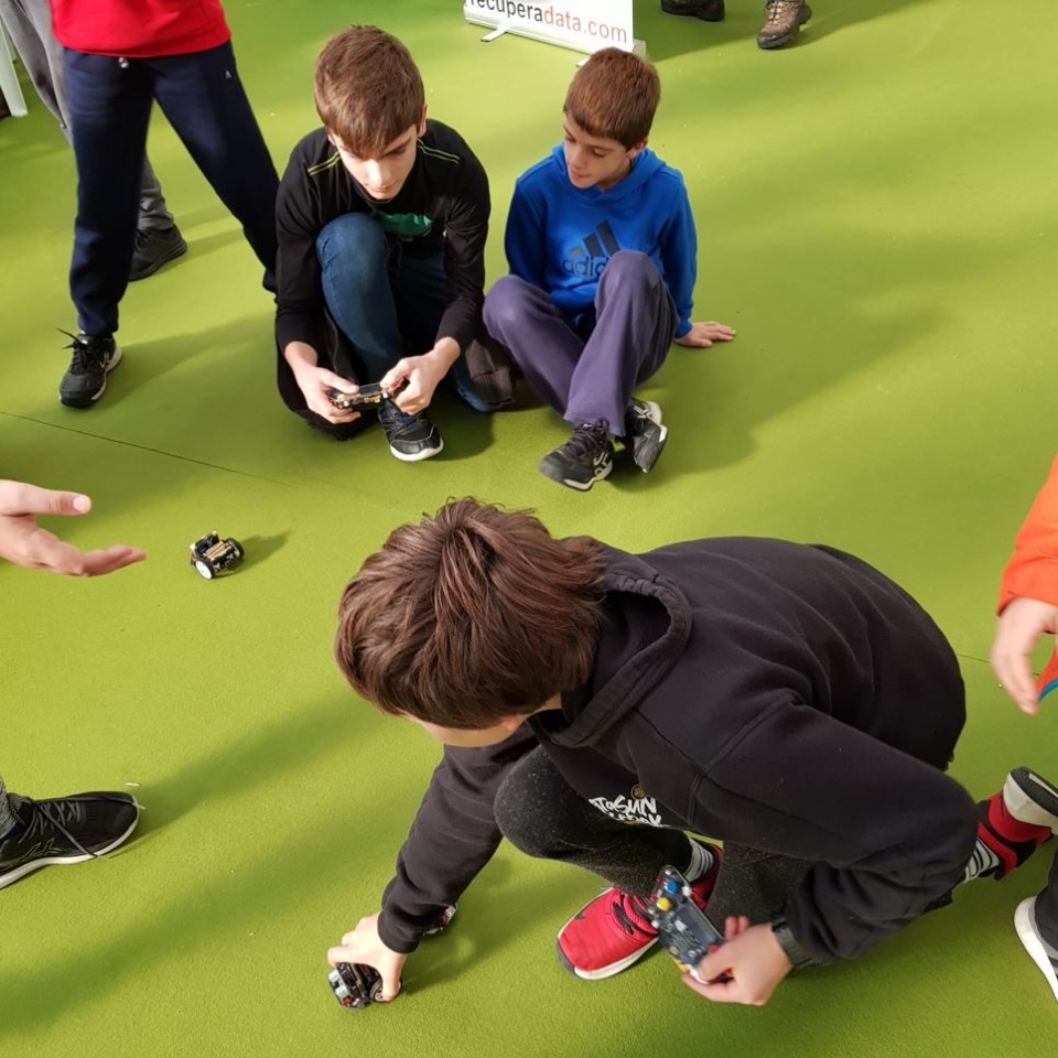 Un grupo de niños jugando en una alfombra verde con alguno de los mecanismos que han ideado