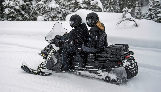 Agarrada al piloto de la moto de nieve