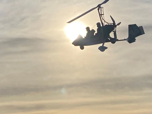 Autogiro volando al atardecer 