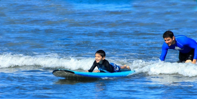  Child learning to surf with the instructor 