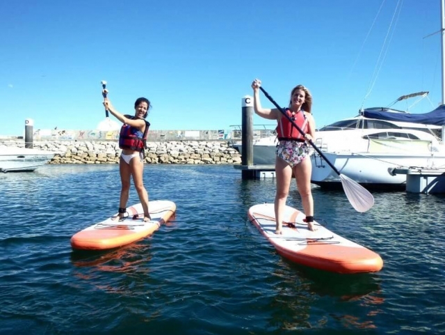 Amigas pasando un ramarro divertido haciendo paddle board