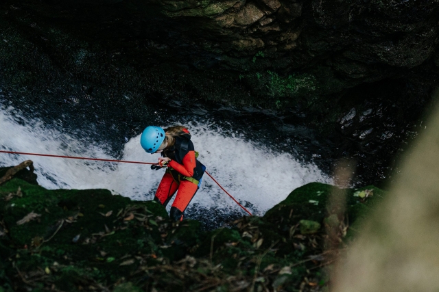 Chica descendiendo con rápel por la roca