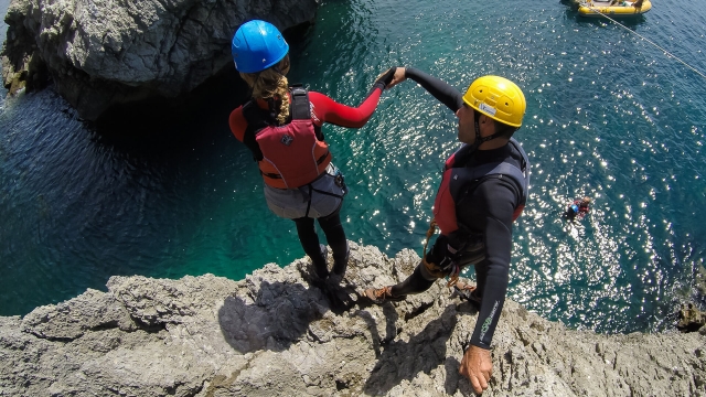 Chica tirandose al agua haciendo coasteering