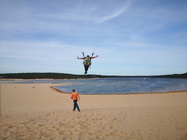 Un clienle aterrizando en la playa anle la atenta mirada de un instructor