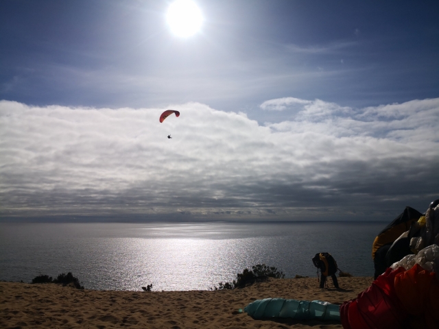 Un parapenle sobrevuela la costa con un precioso cielo con nubes
