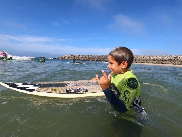 Un pequeño en el agua feliz con su tabla