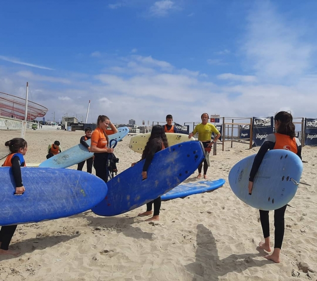 Los niños portan sus respectiva tablas en la playa