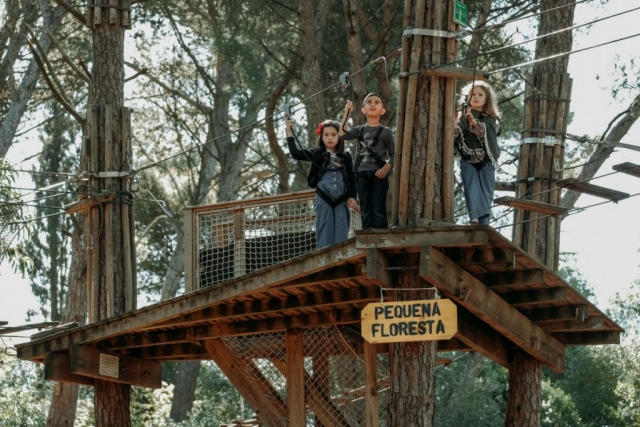 Tres niños esperan su turno en lo alto de una plataforma de madera
