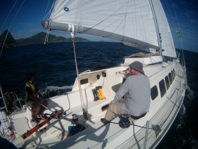  Hombre sentado en las barras laterales de un velero en el mar 